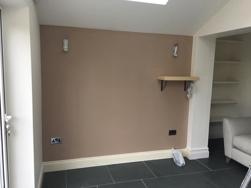 Freshly painted living room with a warm taupe feature wall, built-in alcove shelving and crisp white skirting